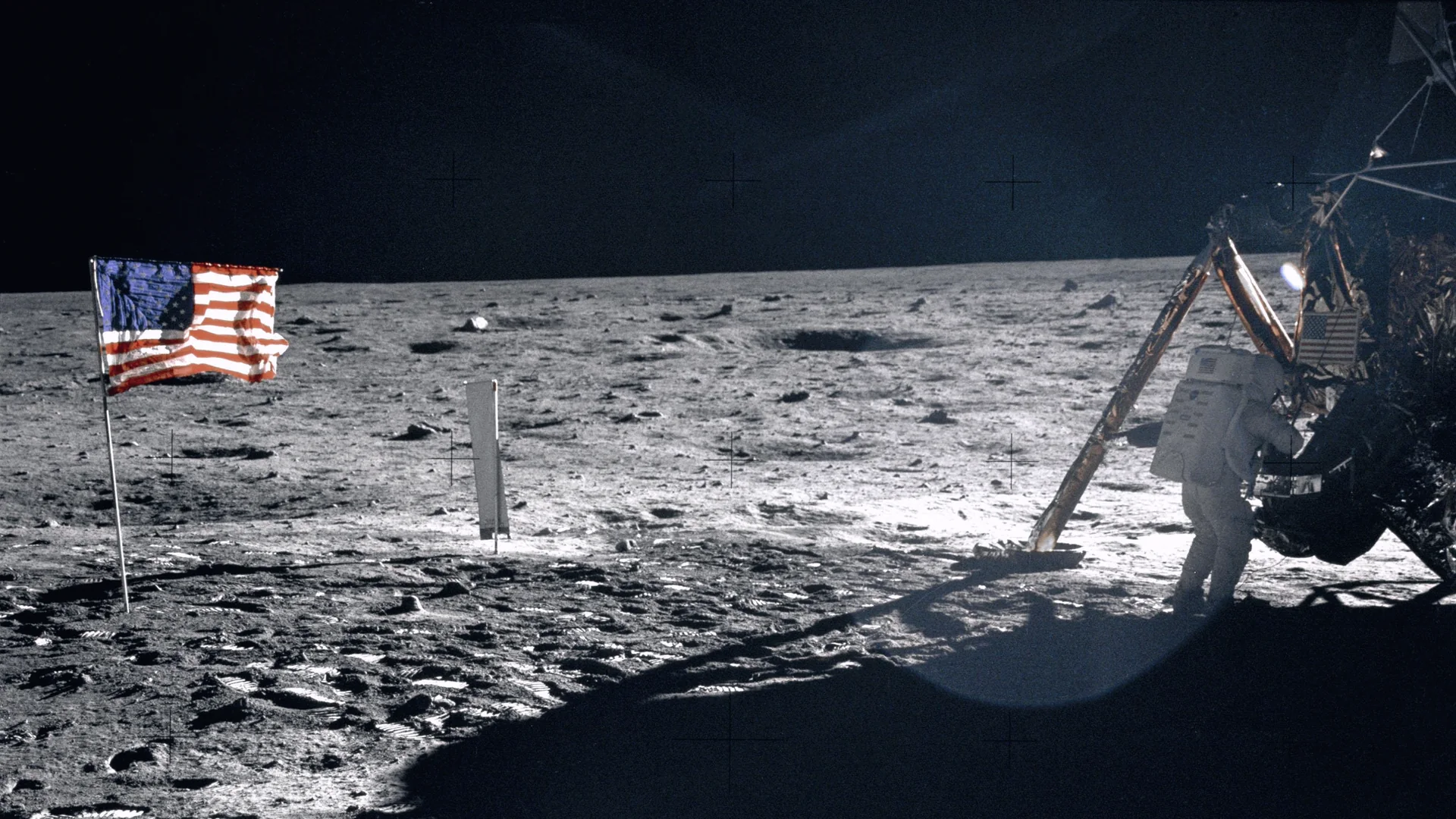 Apollo 11: the United States flag planted in the lunar soil, and an astronaut working at the lunar module.